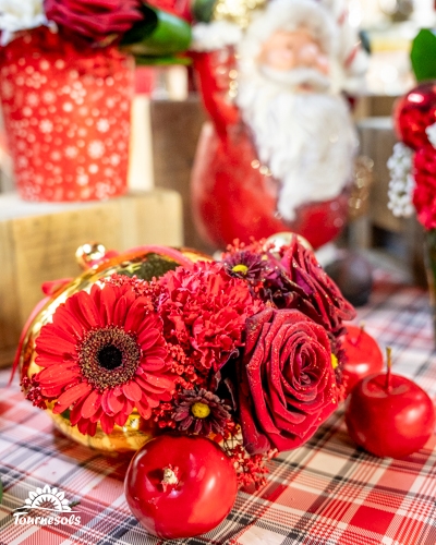 Bouquet de fleurs rouges avec décorations de Noël sur une table à carreaux.